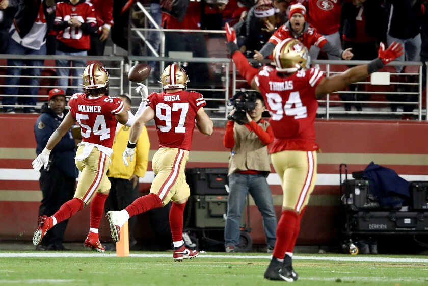 49ers linebacker Fred Warner flips the ball in the end zone after returning an interception 46 yards for a touchdown late in the second quarter.