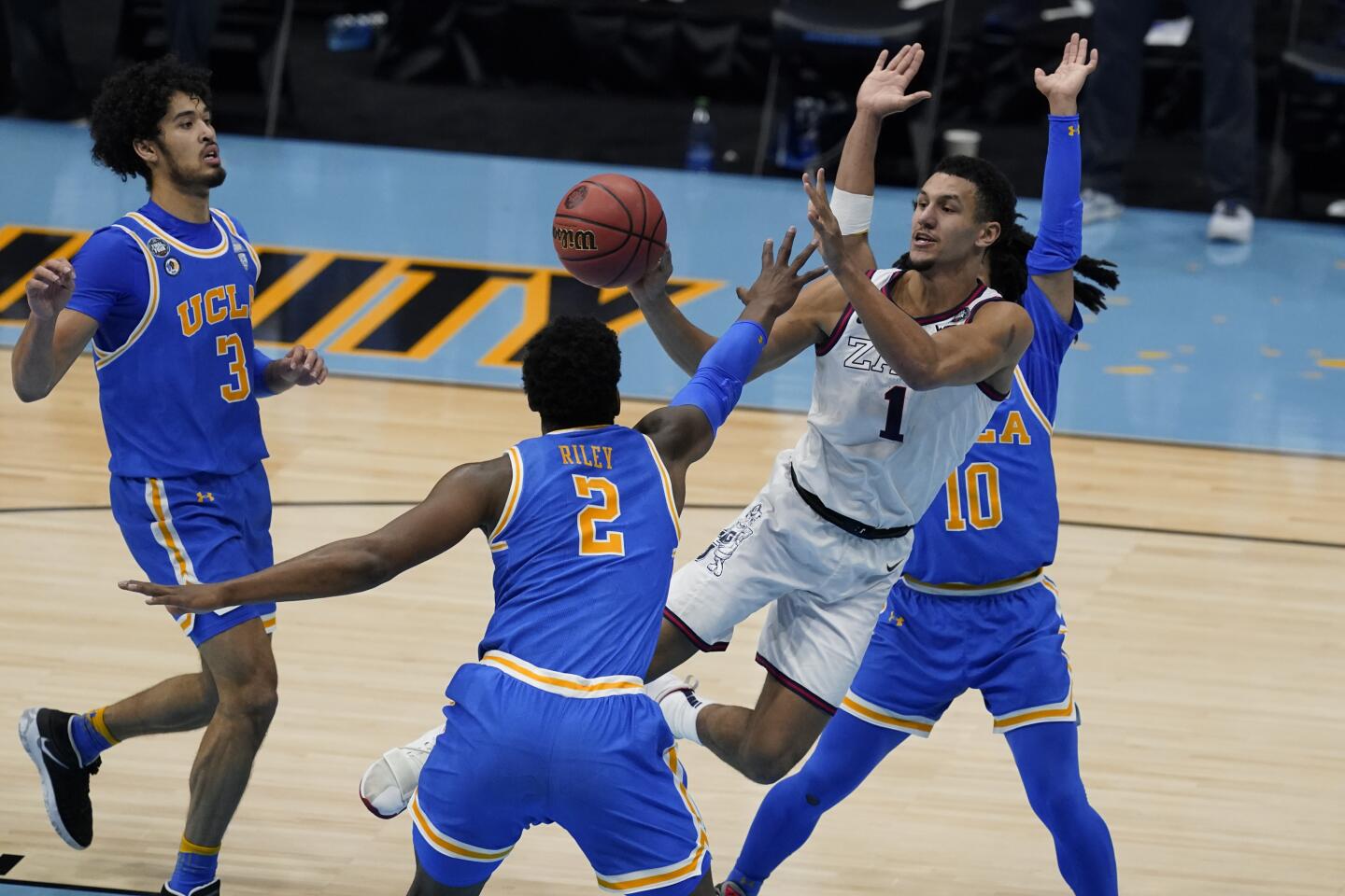 Gonzaga guard Jalen Suggs (1) passes between UCLA guard Johnny Juzang (3), forward Cody Riley (2) and guard Tyger Campbell (10) during the first half of a men's Final Four NCAA college basketball tournament semifinal game, Saturday, April 3, 2021, at Lucas Oil Stadium in Indianapolis. (AP Photo/Darron Cummings)