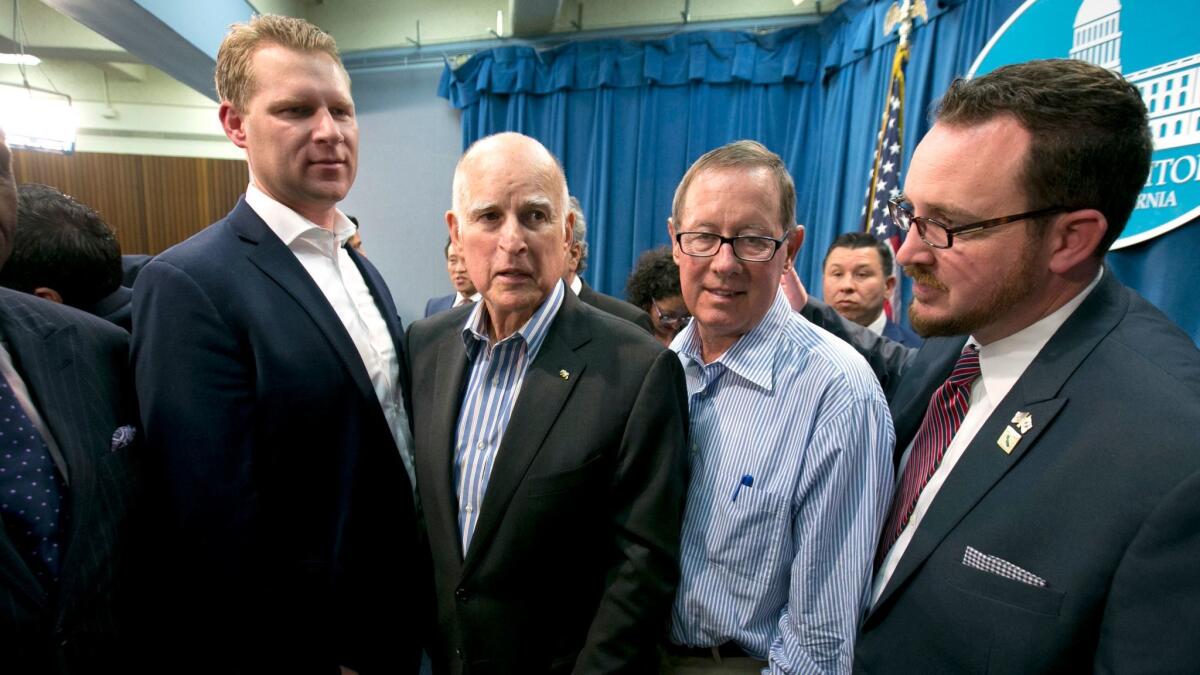 Gov. Jerry Brown, center left, flanked by Republicans who voted for the cap-and-trade extension: Assembly GOP leader Chad Mayes of Yucca Valley, Sen. Tom Berryhill of Modesto and Assemblyman Devon Mathis of Visalia. (Rich Pedroncelli / Associated Press)