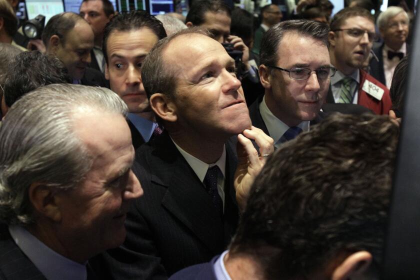 FILE - Then-Nielsen Company CEO David Calhoun, center, watches progress as he waits for the company's IPO to begin trading, Jan. 26, 2011, on the floor of the New York Stock Exchange. Calhoun will be stepping down at the end of the year from the top job at Boeing, which is under pressure from major airlines wanting to know how the company plans to fix problems in the manufacturing of its planes. (AP Photo/Richard Drew, File)
