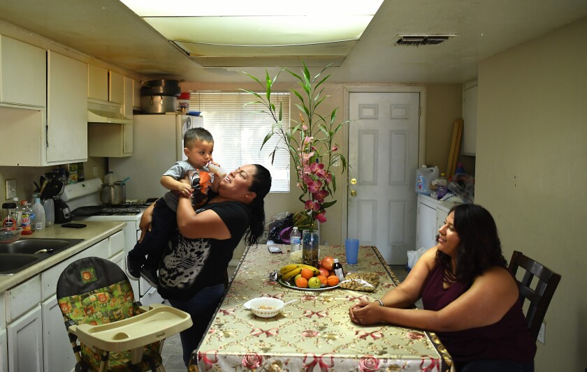 Araceli Reyes sostiene a su nieto Ethan Bello mientras la madre del niño, Edith Mata, observa.