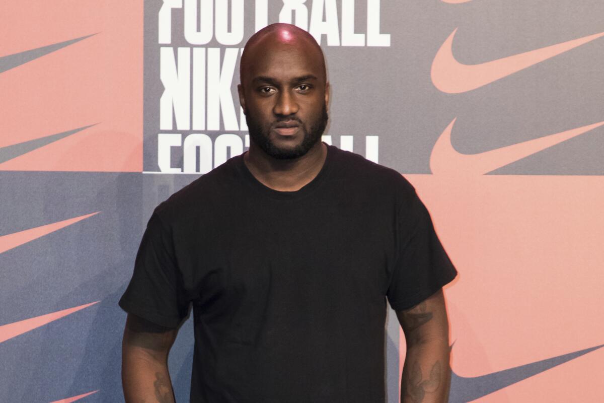 A bald man with a beard posing in a black T-shirt