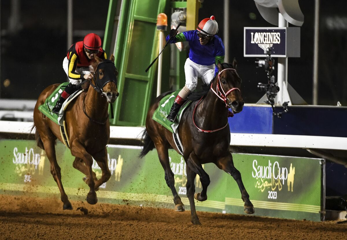 Jockey Yutaka Yoshida raises his right arm in triumph after riding Panthalassa to victory in the Saudi Cup on Saturday.