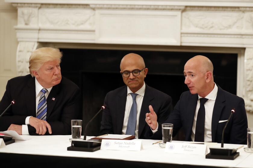 FILE - In this June 19, 2017, file photo President Donald Trump, left, and Satya Nadella, Chief Executive Officer of Microsoft, center, listen as Jeff Bezos, Chief Executive Officer of Amazon, speaks during an American Technology Council roundtable in the State Dinning Room of the White House in Washington. Amazon and Microsoft are battling for a $10 billion opportunity to build the U.S. military its first war cloud. (AP Photo/Alex Brandon, File)