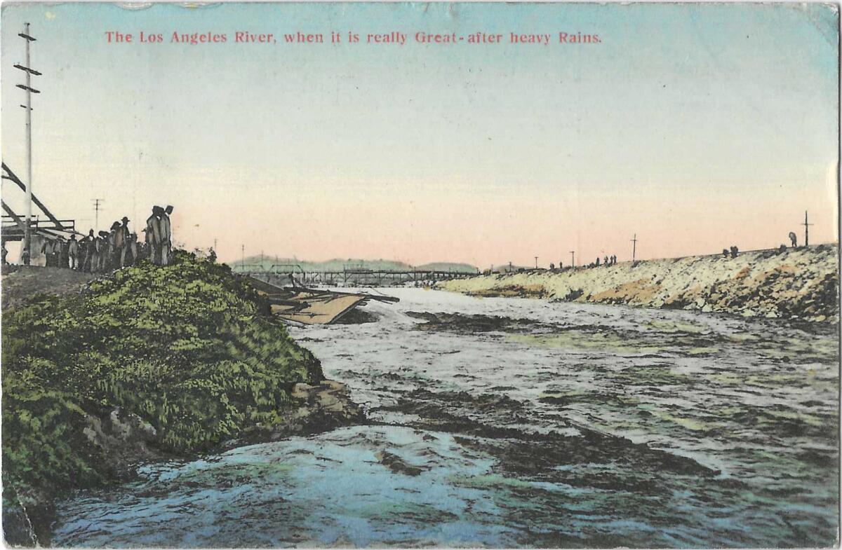 Water rushes in the L.A. River Basin, with a bridge in the background and people on either bank