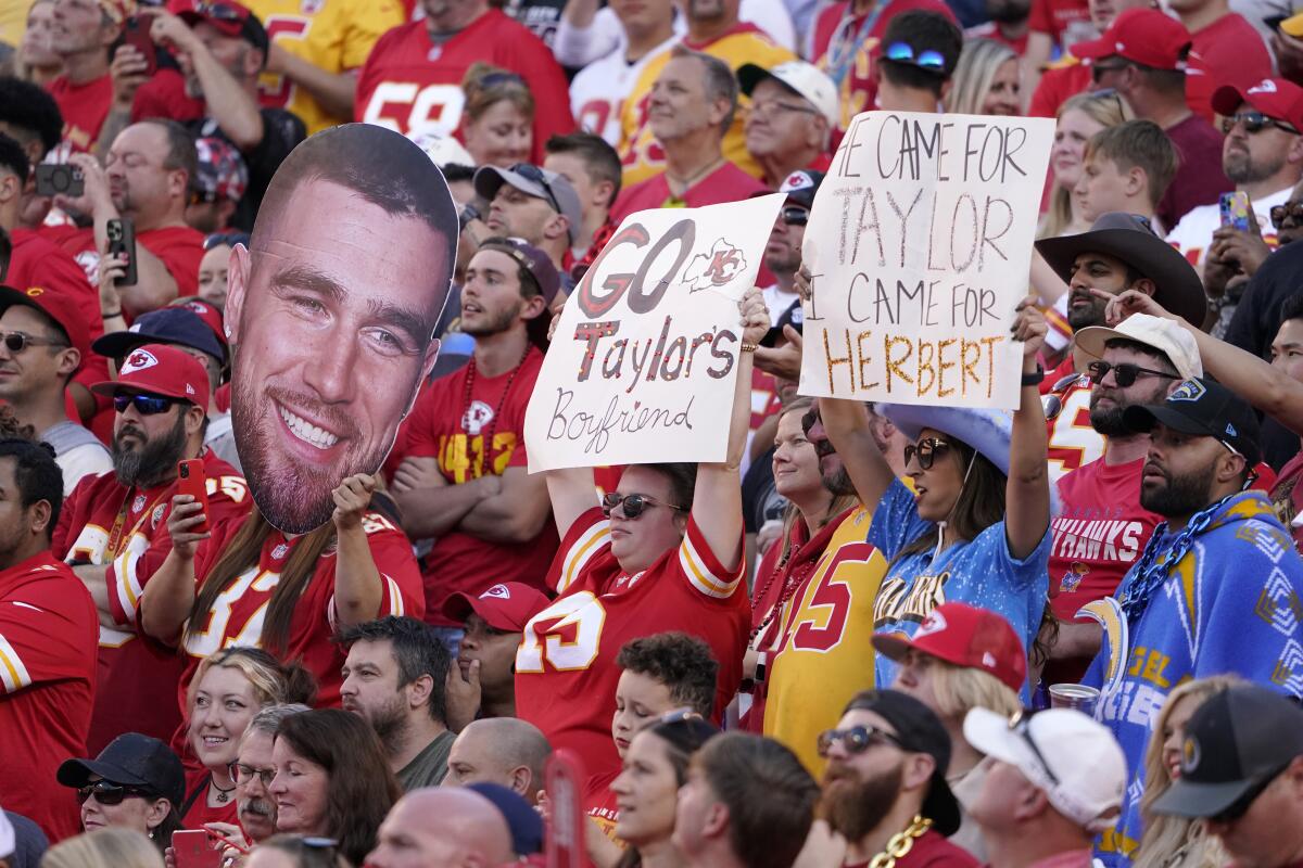 Fans hold signs referring to Travis Kelce and Taylor Swift during a game between the Chiefs and Chargers in Kansas City, Mo.