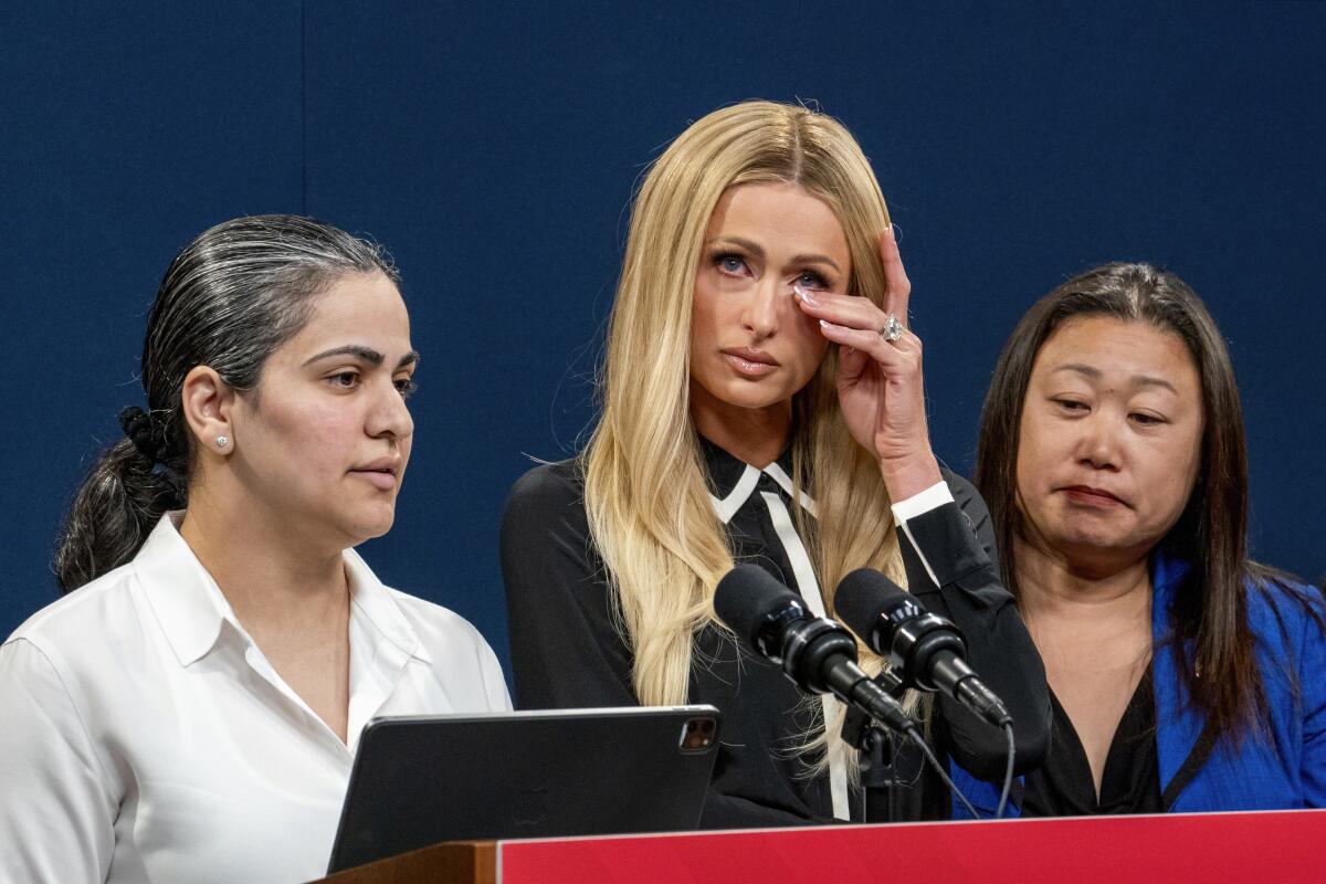 Paris Hilton wipes her eyes during a news conference with state Sen. Aisha Wahab, left, and state Sen. Janet Nguyen.
