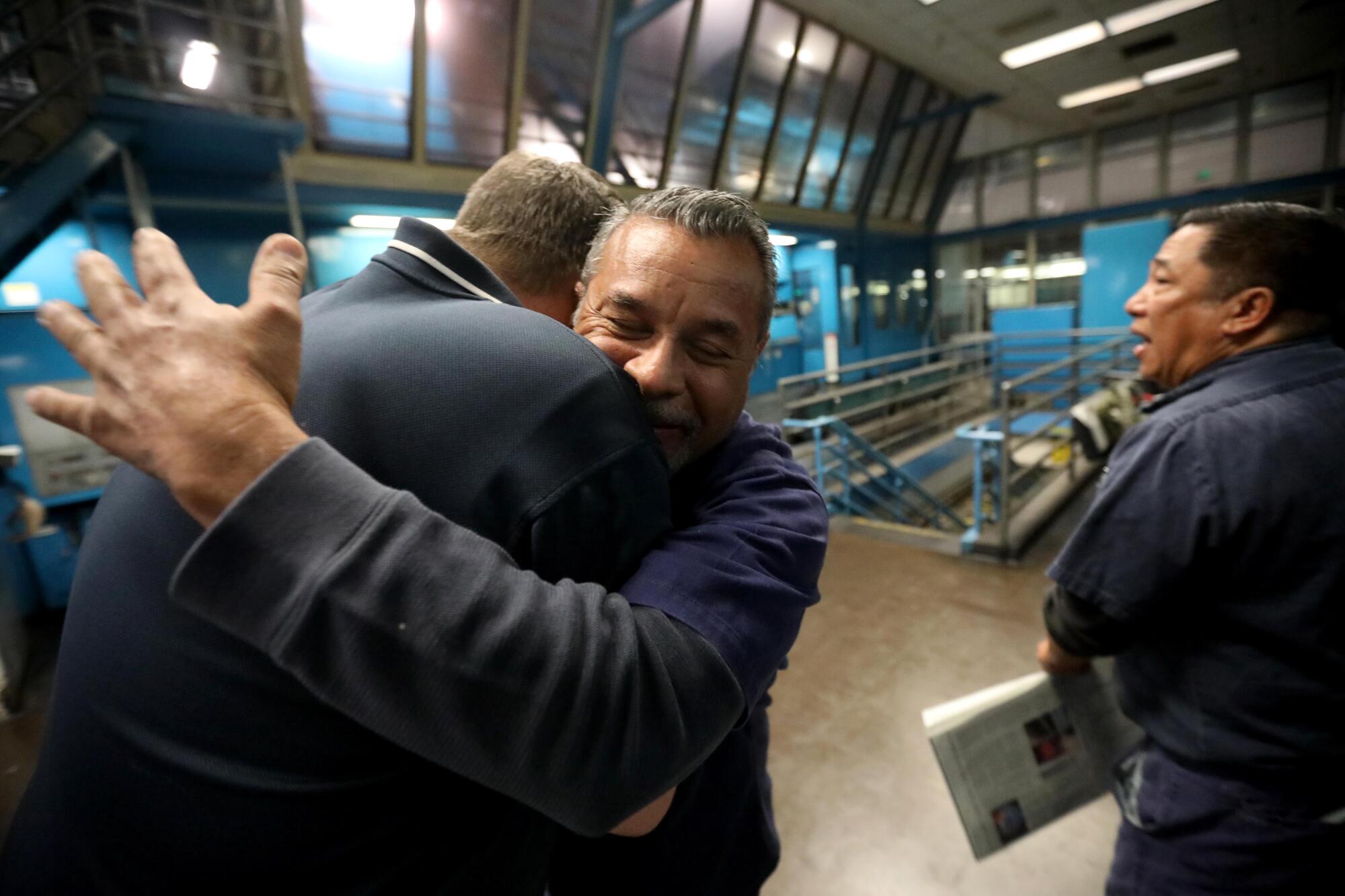 Pressman Alex Borjon hugs pressroom shift supervisor Kal Hamalainen goodbye.