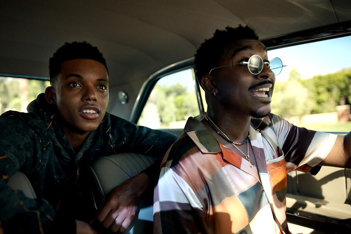 Two young men look excited while driving in a scene from "Bel-Air."