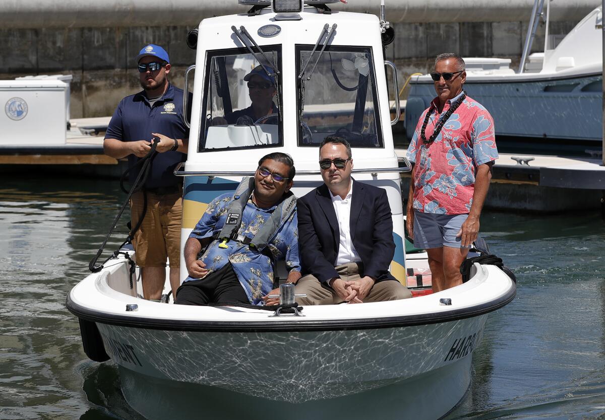 Bhumit Shah, a disabled boater, sits with Mayor Kevin Muldoon, from left, after demonstrating a lift.