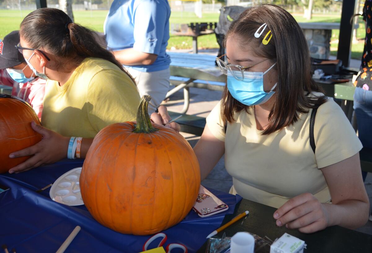 Dina Silva, 18, paints her pumpkin during the Helpful Hondaween Celebration for youths on Friday.