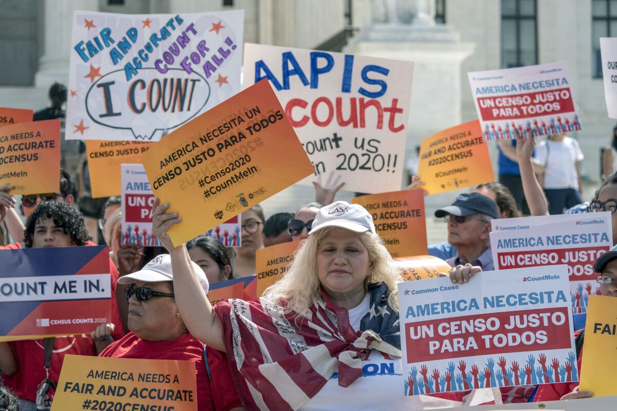People hold up signs at a 2019 rally for a fair and complete census.