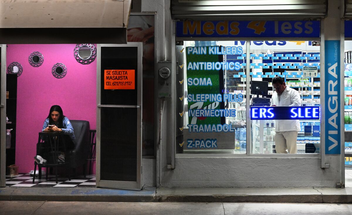 The outside of a pharmacy, with writing in English on its windows indicating it sells pain killers and other medications