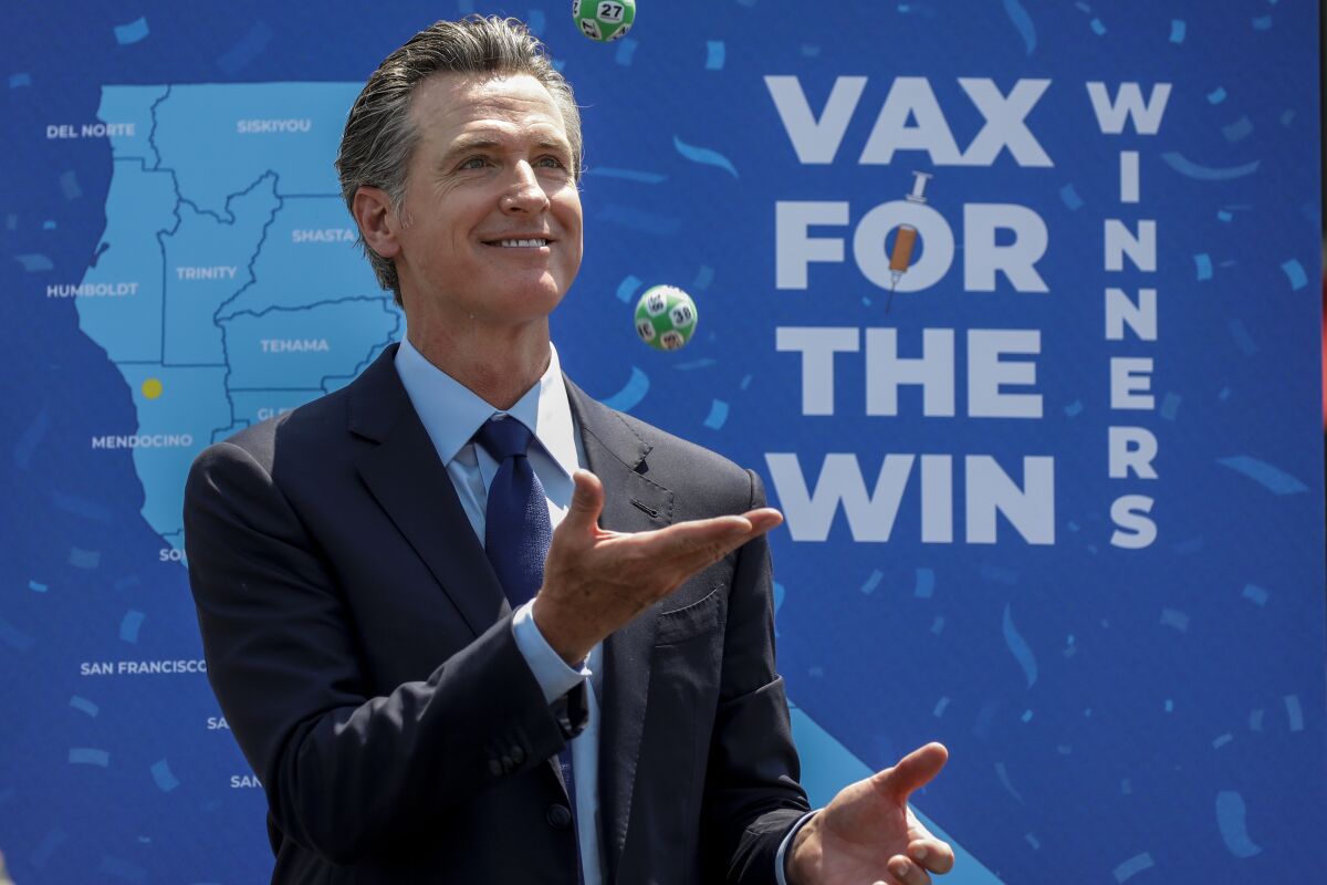 Gov. Gavin Newsom juggles numbered balls used in a lottery-style giveaway for vaccinated Californians