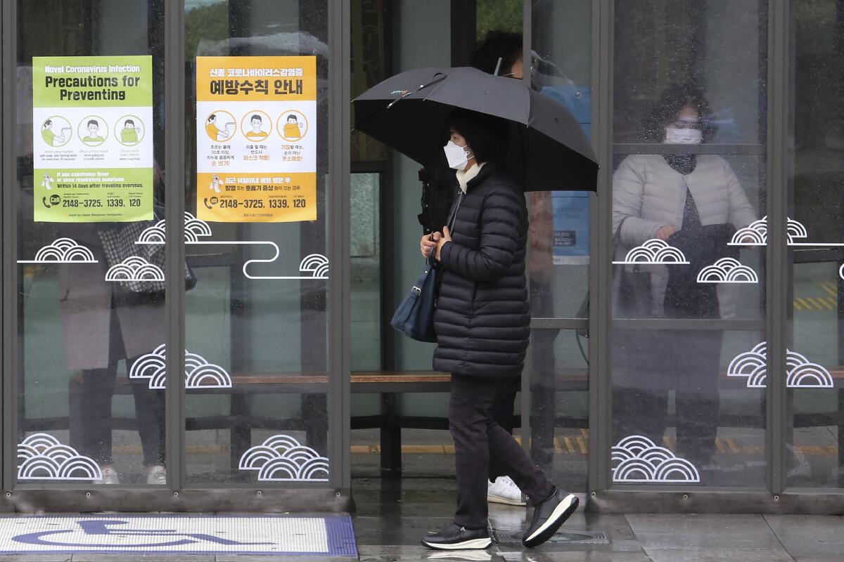 Una mujer con mascarilla pasa junto a carteles sobre precauciones contra el neuvo coronavirus en una estación de autobús en Seúl, Corea del Sur, el martes 25 de febrero de 2020. (AP Foto/Ahn Young-joon)
