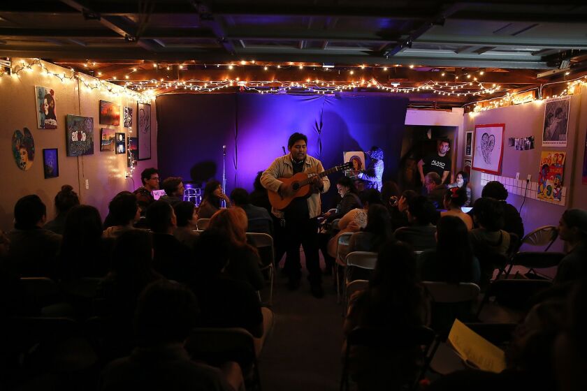Dozens of people crowd Eric Contreras' parents' garage in Bell as Julio Marquez performs folk songs at an open-mic night called Alivio, Spanish for "relief."