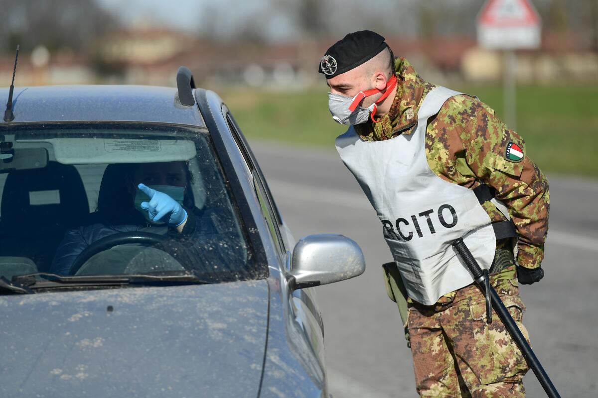 An Italian soldier talks with a driver at a checkpoint