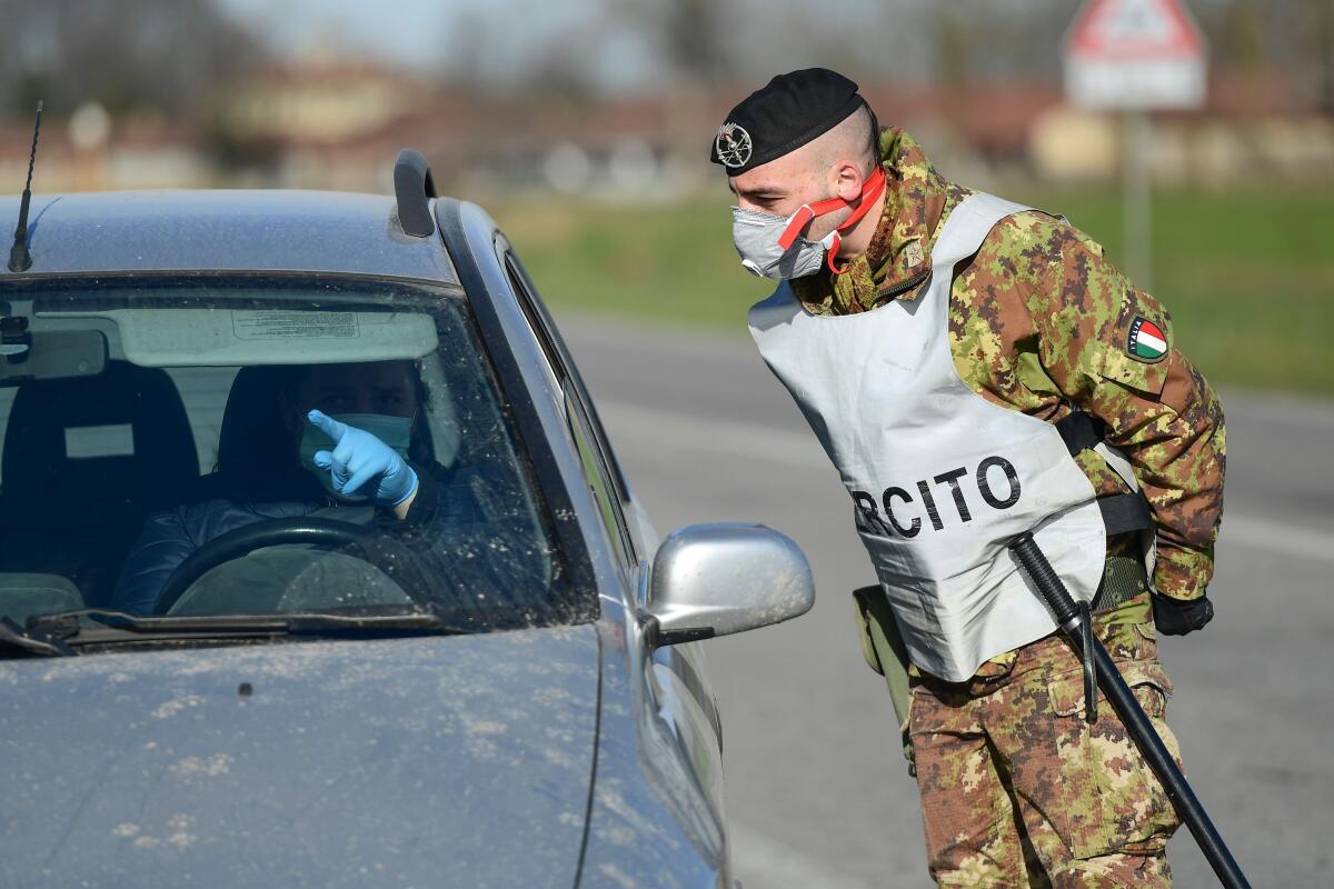 An Italian soldier talks with a driver at a checkpoint outside Castiglione d'Adda, Italy, on Feb. 27. Two people in the same Atlanta-area household, including a man who recently traveled to Italy, have contracted the novel coronavirus, Georgia officials confirmed.