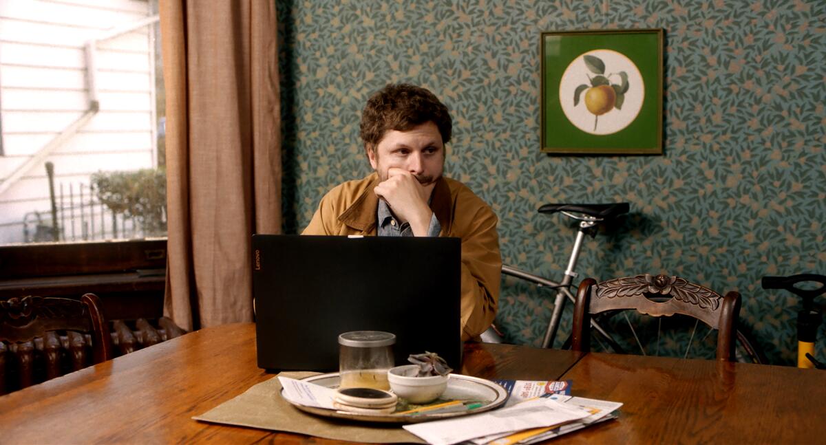 A distracted man sits in front of a laptop.