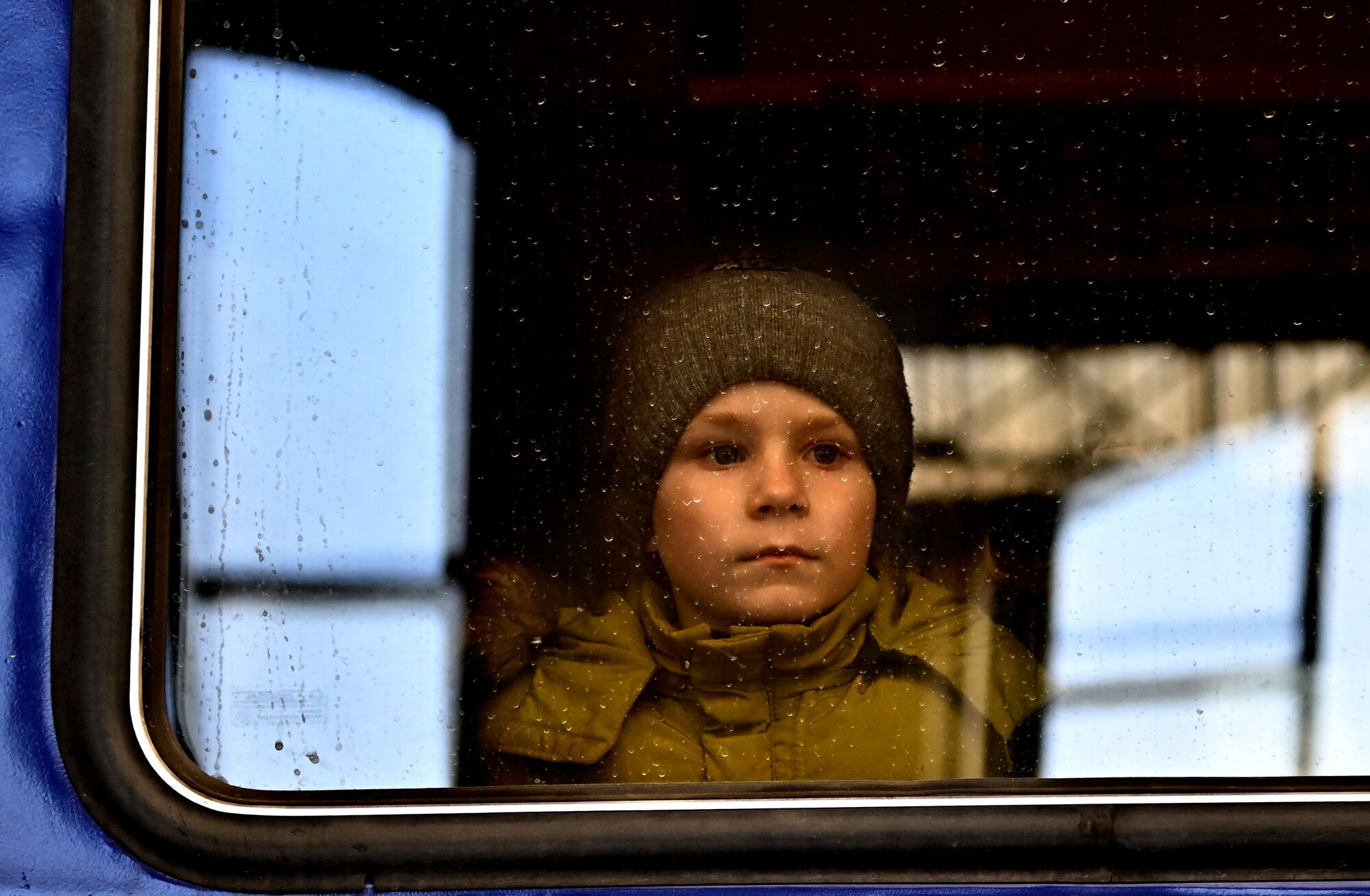 A child in a hat looks out a window
