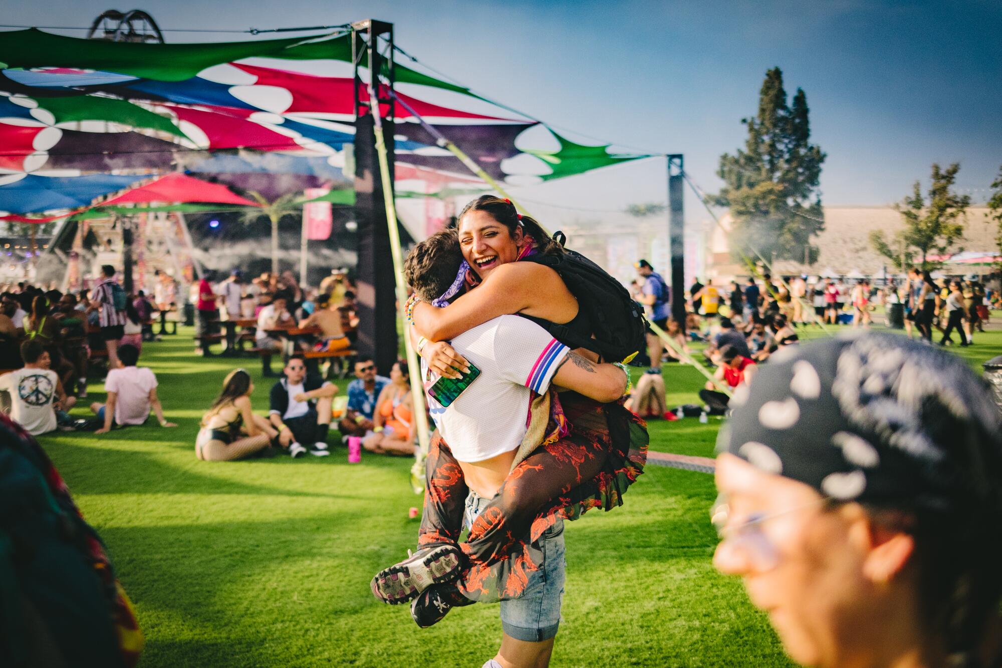 Two people embracing on a lawn at a festival.