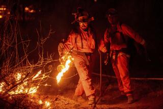 An inmate firefighter from the Trinity River Conservation Camp uses a drip torch to slow the Fawn Fire burning north of Redding, Calif. in Shasta County, on Thursday, Sept. 23, 2021. (AP Photo/Ethan Swope)