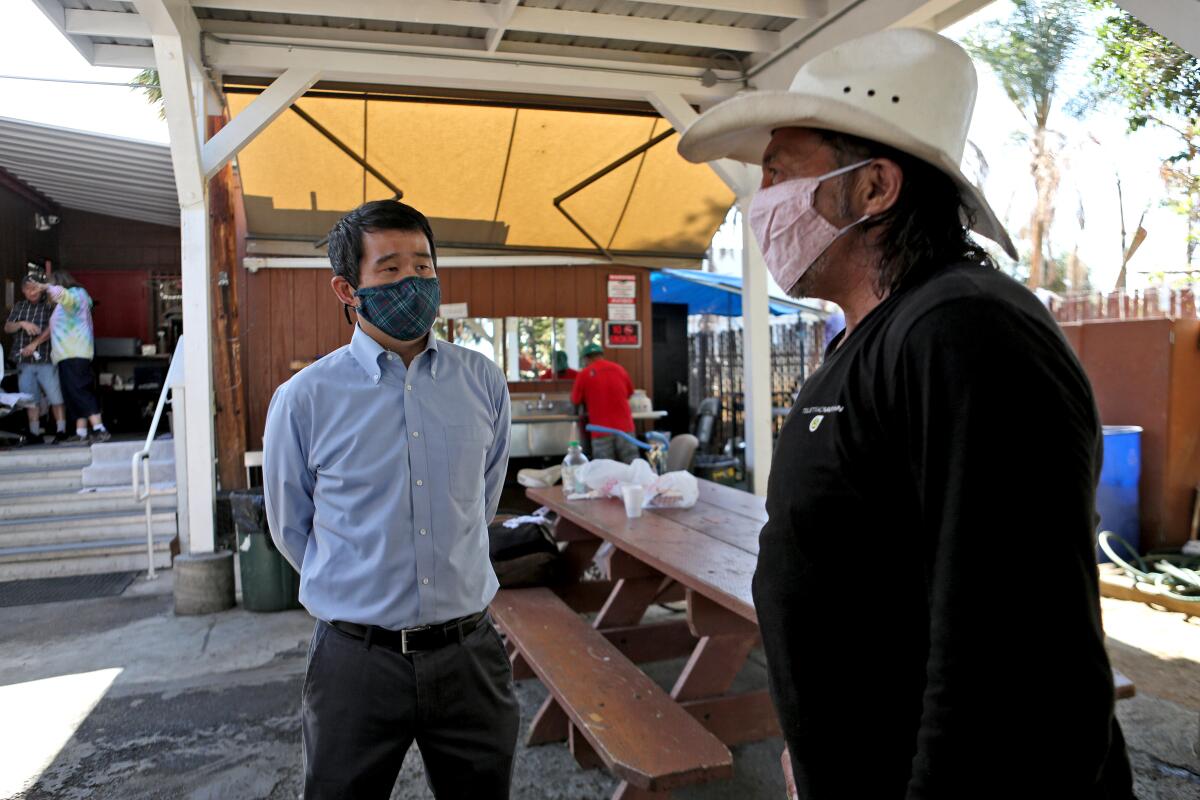 State Sen. Dave Min, left, speaks with Ray Hernandez during a tour of Mary's Kitchen. 
