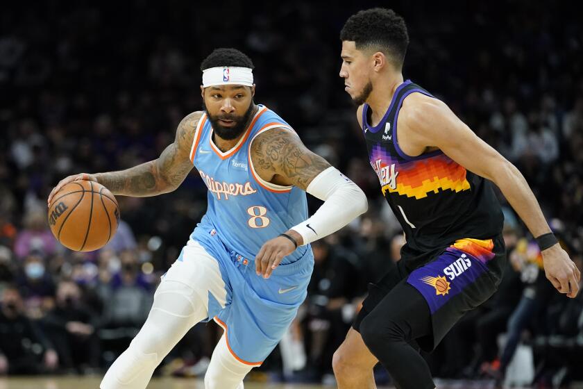 Los Angeles Clippers forward Marcus Morris Sr. (8) drives on Phoenix Suns guard Devin Booker (1) during the second half of an NBA basketball game Tuesday, Feb. 15, 2022, in Phoenix. (AP Photo/Matt York)