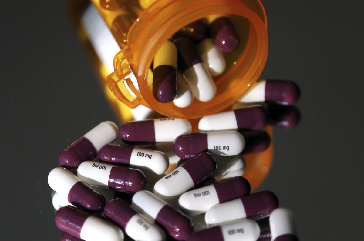Half-white, half-purple pills fall out of a bottle.