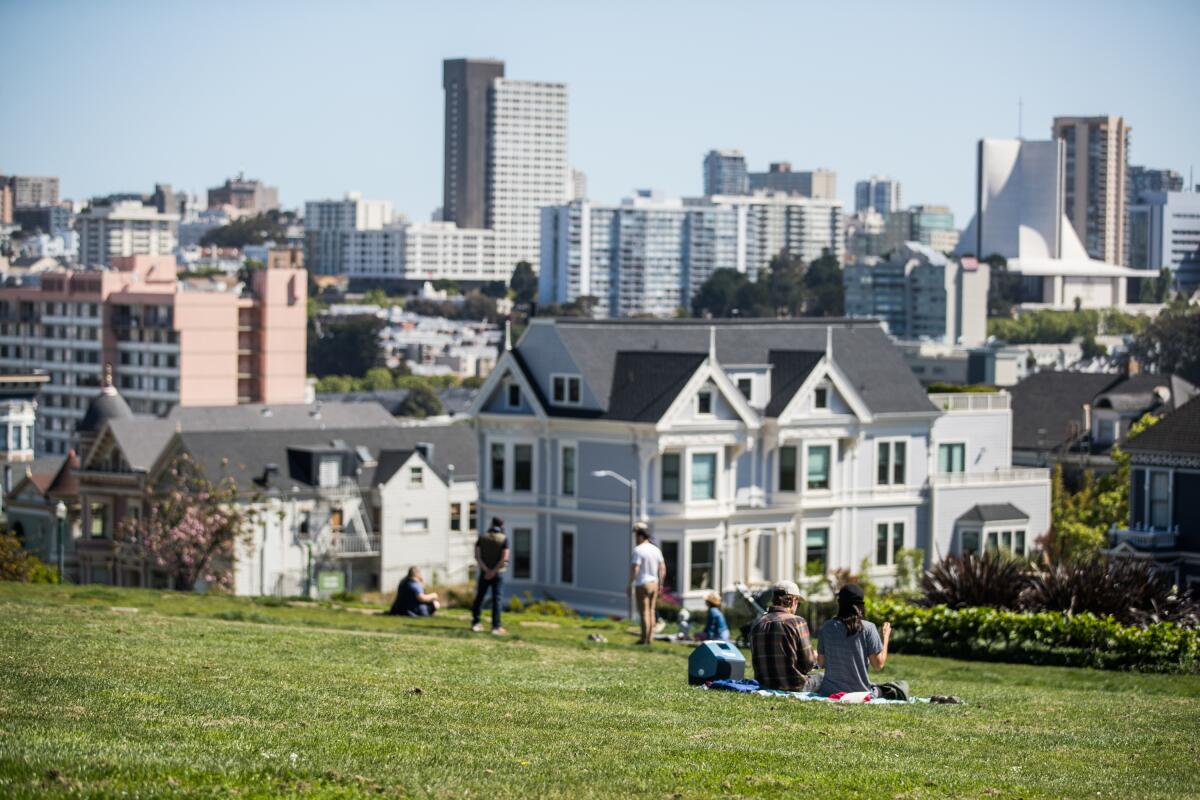 People sit on the grass at San Francisco's Alamo Square Park during the pandemic.