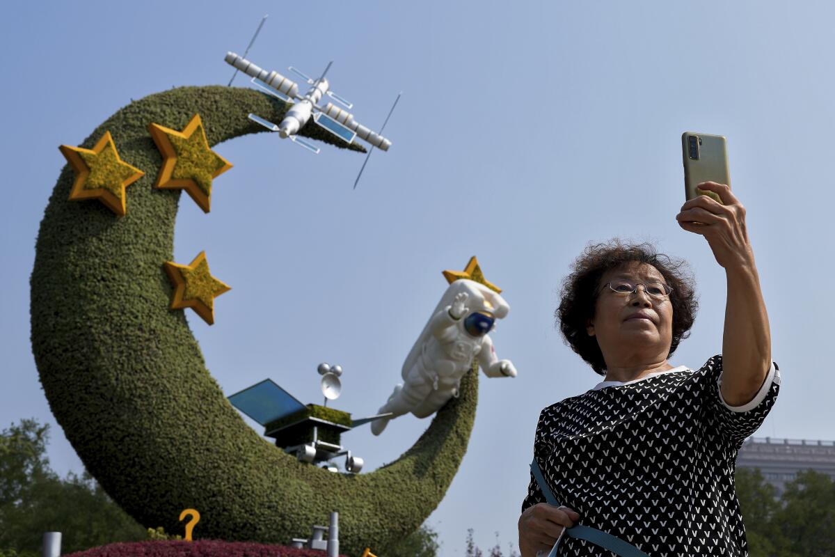 Una mujer se toma una selfie con un arreglo floral sobre los programas espaciales chinos