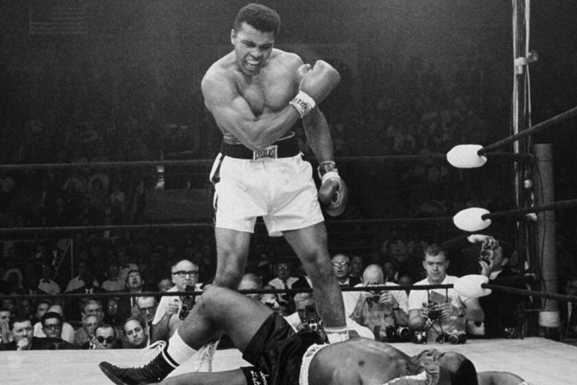 Heavyweight champion Muhammad Ali stands over fallen challenger Sonny Liston, shouting after knocking him down with a short, hard right to the jaw during their bout in Lewiston, Maine, on May 25, 1965.