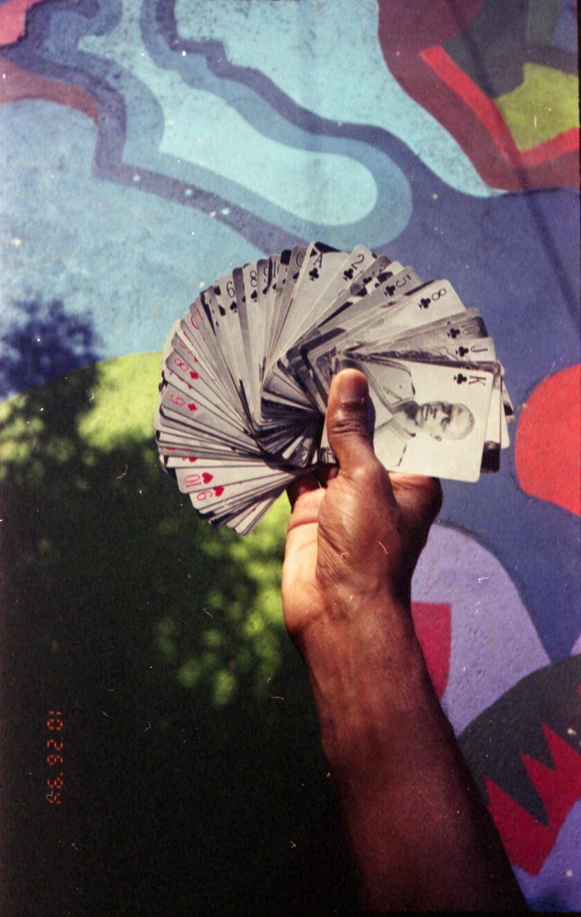 Une main déploie des cartes représentant des portraits en ferrotype.