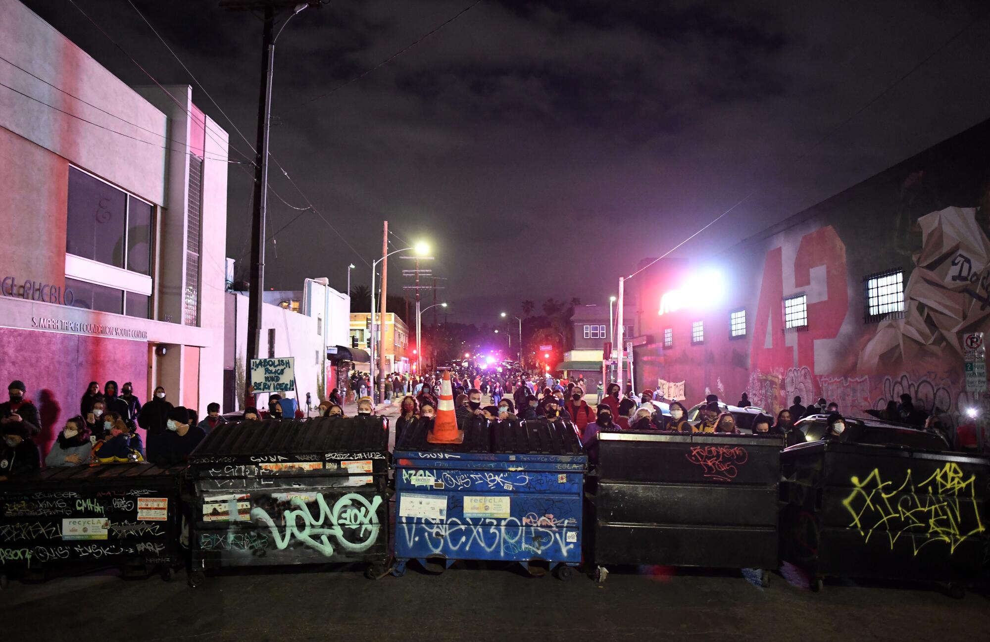 Protesters behind a dumpster barricade. 