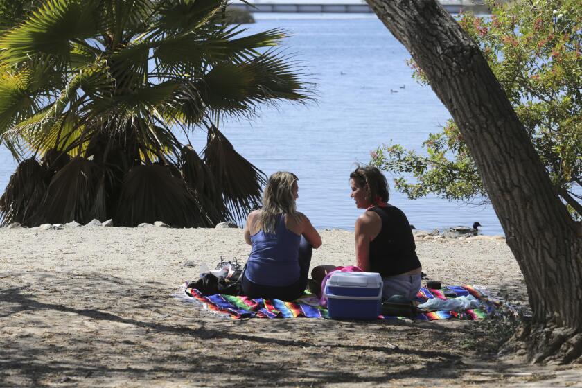 La Mesa, CA - March 17:New found friends Mallory Green (left) and Stacie Nowak enjoy the sunshine and temporate temperatures as they have a picnic beside Lake Murray on Thursday, March 17, 2022 in La Mesa, CA. "This is the best place to be, literally the best spot," Mallory said. (Bill Wechter /For The San Diego Union-Tribune)