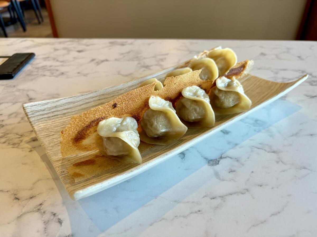 Pan-fried dumplings at Jiou Chu feature a crispy lace of starch around the bottom.
