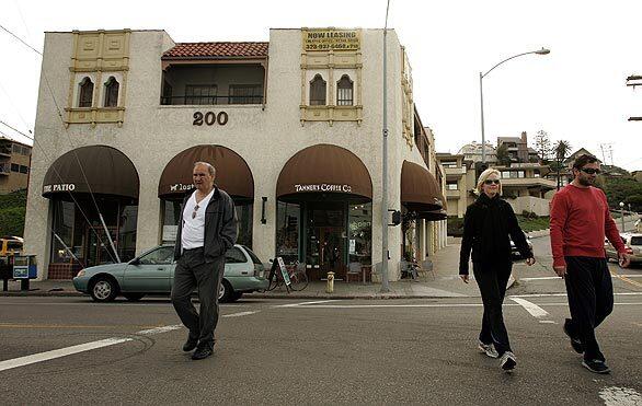 Pedestrians walk across Culver Boulevard, away from the Tanner Coffee Co. The building is next to the site of planned development to upgrade the quaint downtown along the boulevard.