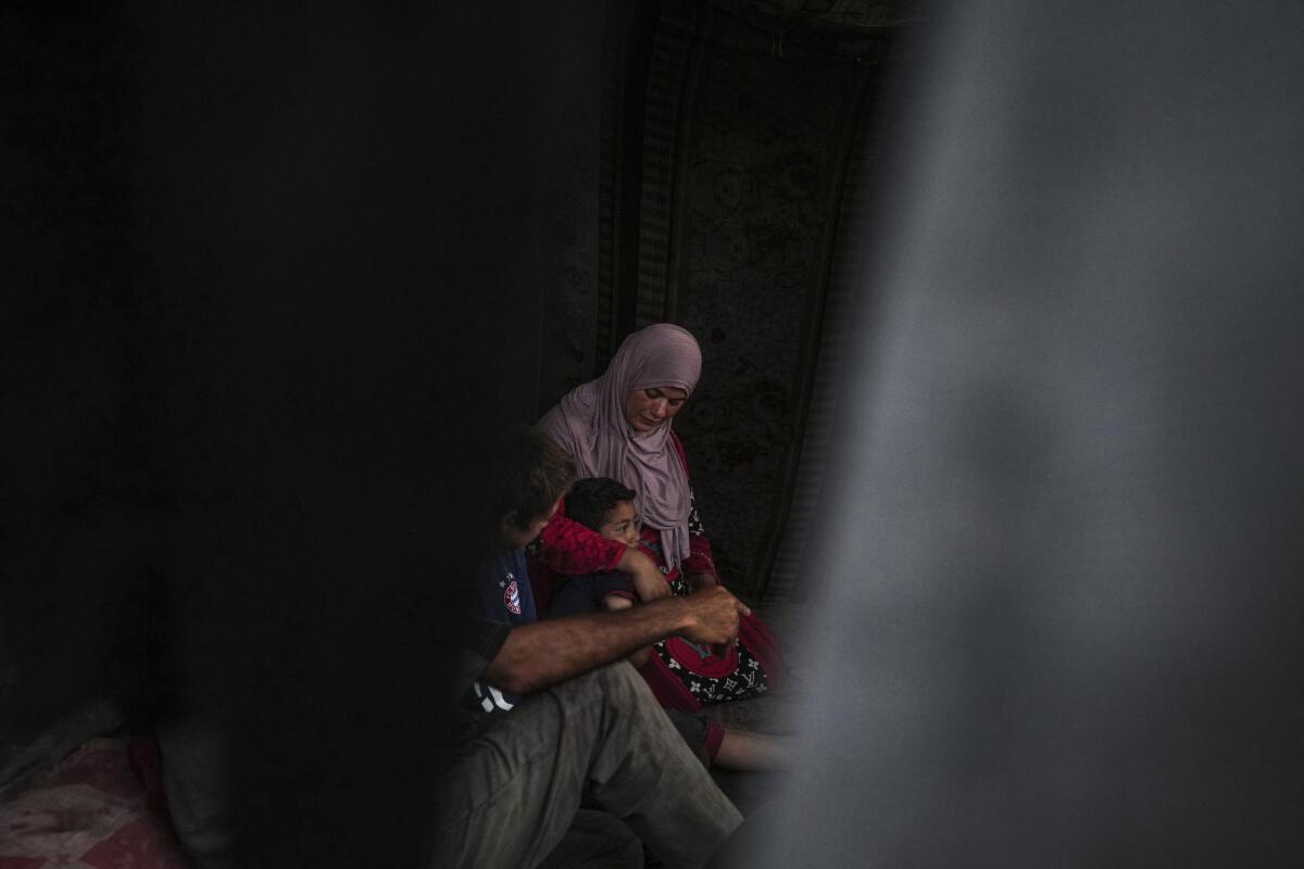 A woman sits with her displaced family in Gaza.