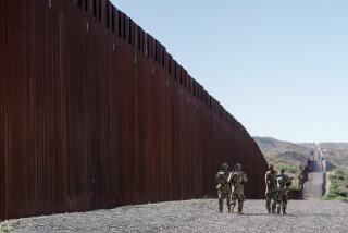 Four members of Arizona Border Recon, a civilian patrol group, walk in the shadow of fencing along the U.S.-Mexico border west of Nogales, Ariz, on Oct. 29, 2023. (Jia Li / Scripps News)