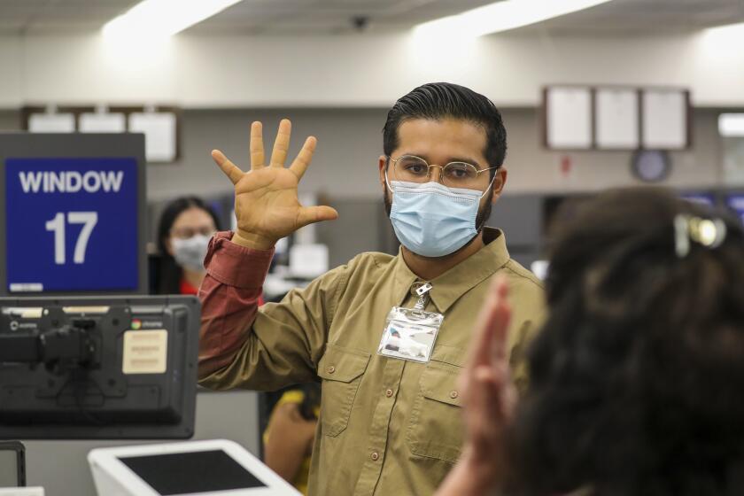 WESTMINSTER, CA - AUGUST 13: Guillermo Torres, left, administers an eye test at DMV on Thursday, Aug. 13, 2020 in Westminster, CA. (Irfan Khan / Los Angeles Times)