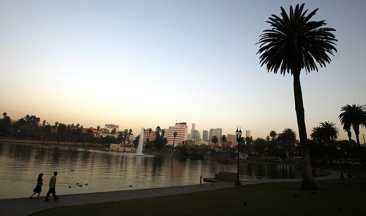 A couple walks along the concrete banks of MacArthur Park Lake in MacArthur Park, where a man was stabbed to death, police say.