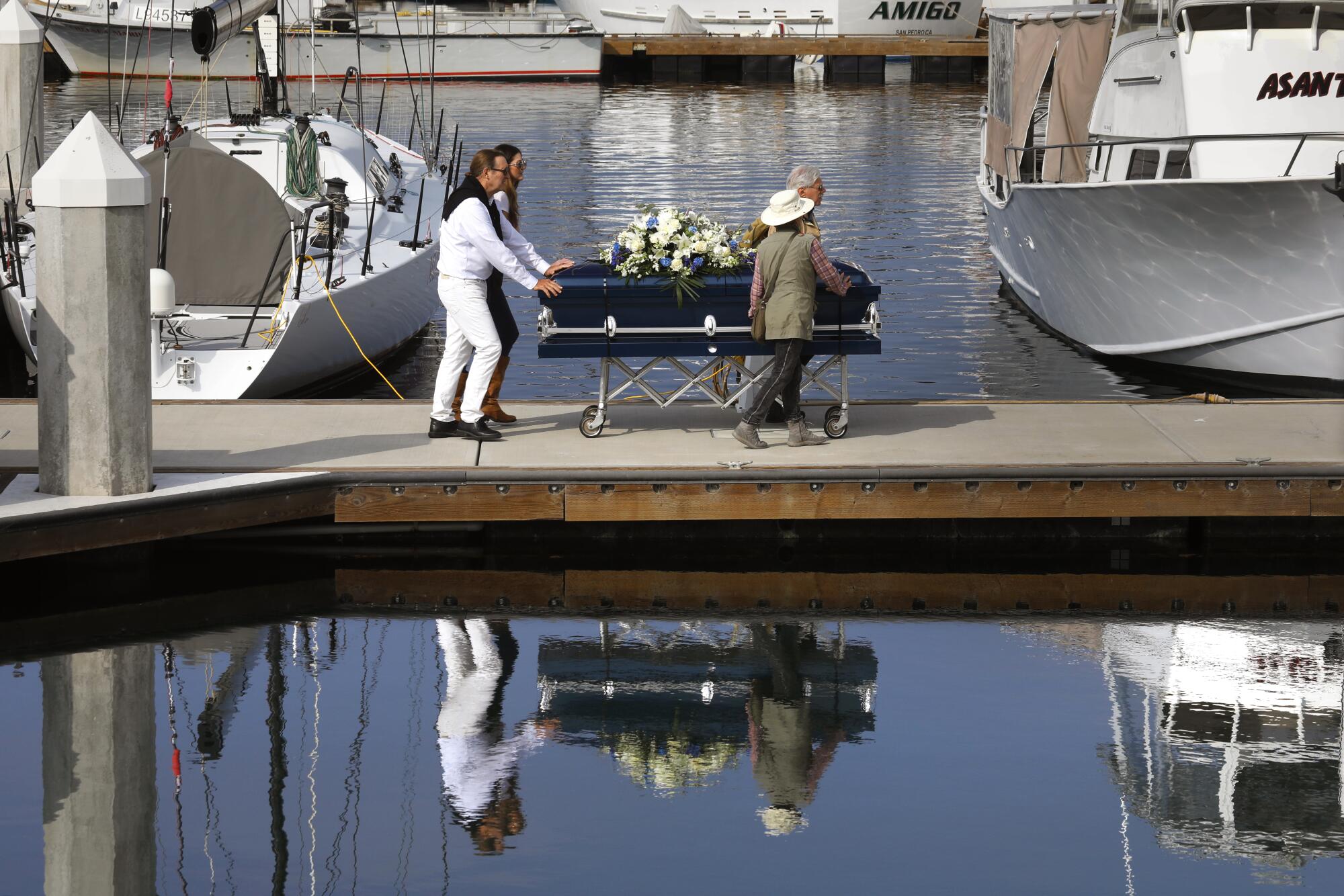 Diane Berol helps move the casket of her husband John Berol to the boat which will they him to his burial site at sea.