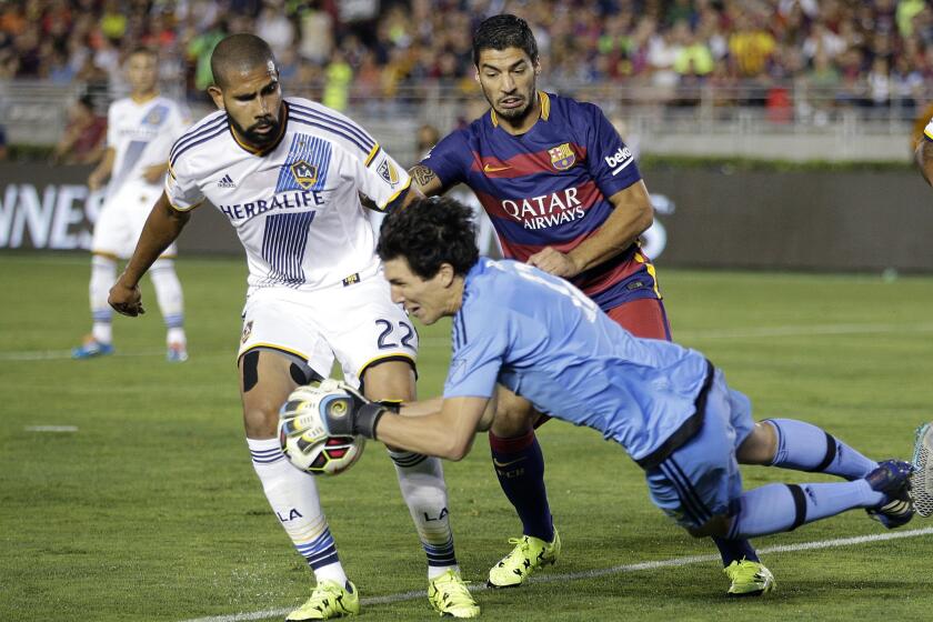 Los Angeles Galaxy goalkeeper Brian Rowe, front, makes a save in front of Galaxy's Leonardo, left, and FC Barcelona's Luis Suarez during the first half of an International Champions Cup soccer match on Tuesday at the Rose Bowl.