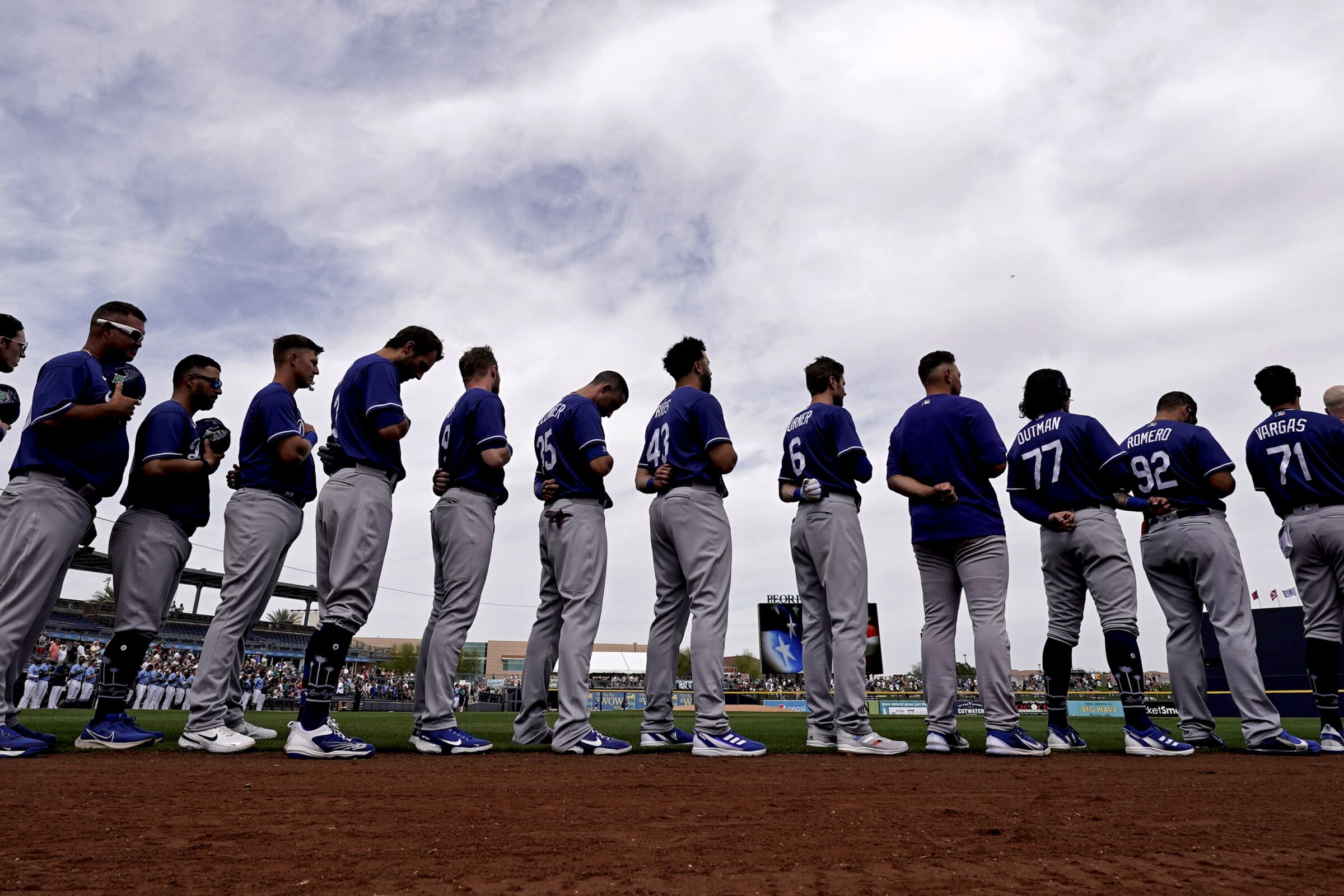 Dodgers players stand for the national anthem before a spring training game against the Seattle Mariners 