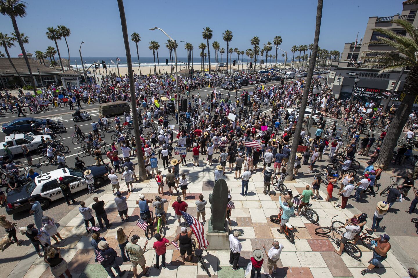A large crowd gathers during a protest of Gov. Gavin Newsom's stay-at-home orders at Main Street and Pacific Coast Highway in Huntington Beach on Friday.