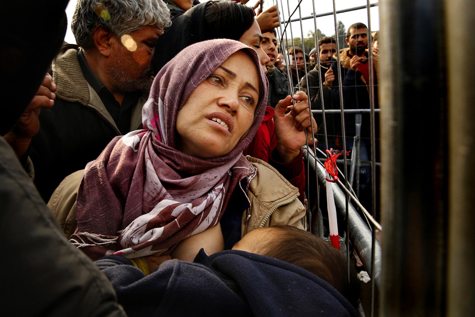 Jamileh Heydari nurses her young son, Matin, in the crush of people against a barricade.