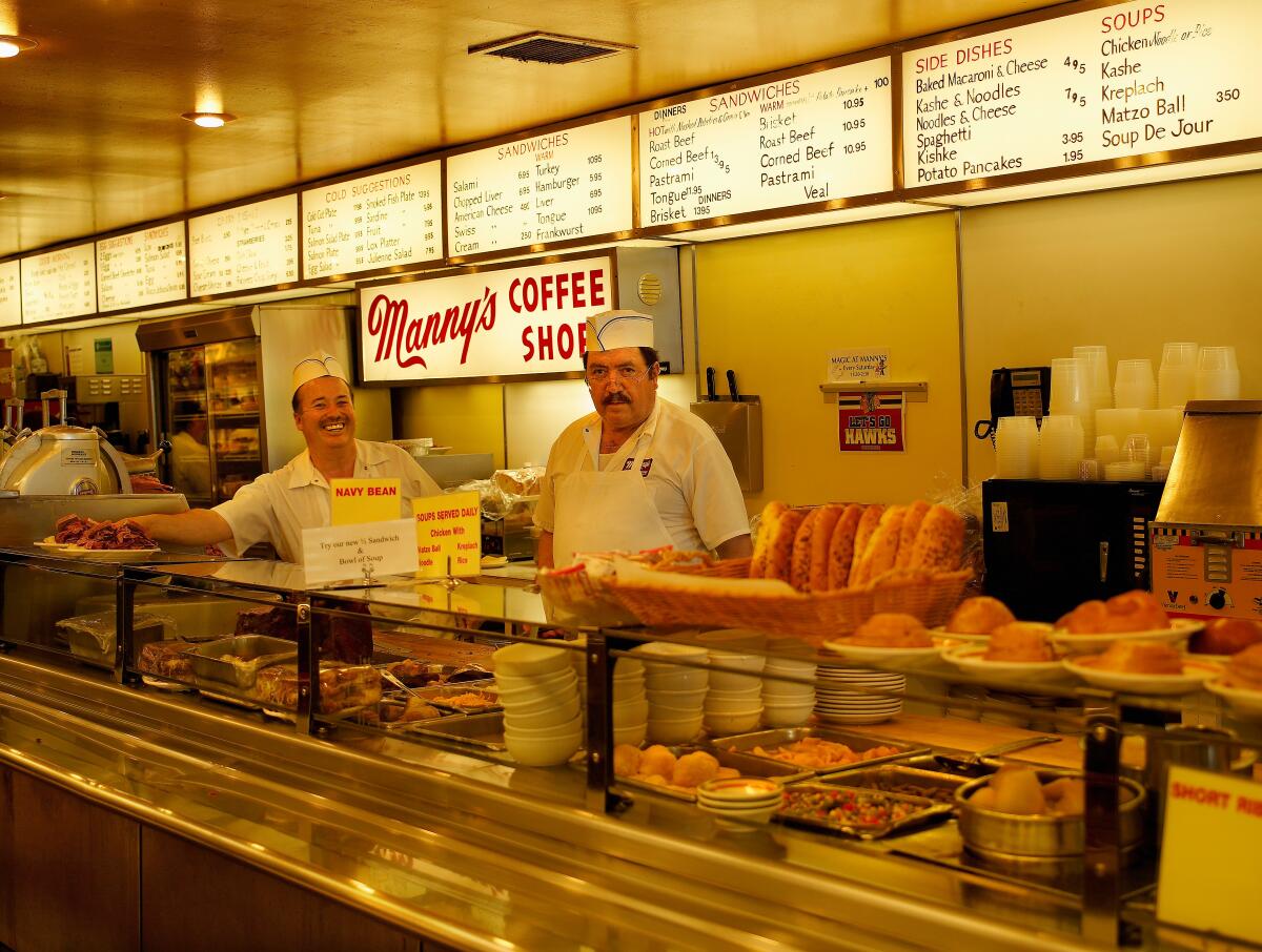 Two employees stand behind the food cases of Manny’s Delicatessen in Chicago.