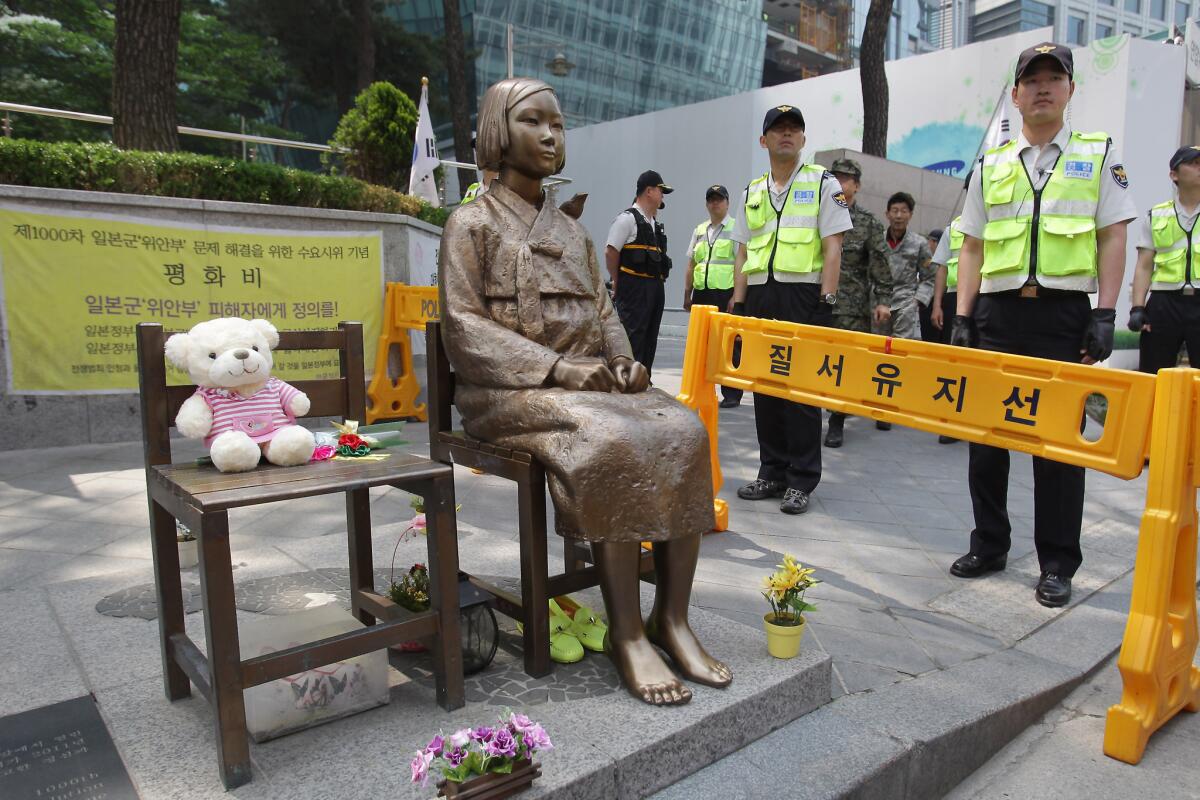 South Korean police stand guard beside a "comfort woman" statue during an anti-Japan rally in front of the Japanese embassy in Seoul.