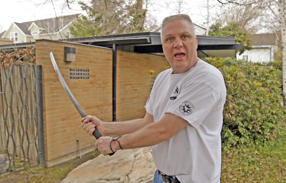 Kent Hendrix, 47, wields his sword near his house in Salt Lake City. Hendrix, a Mormon bishop, came to the aid of a woman who was being attacked in front of his house.