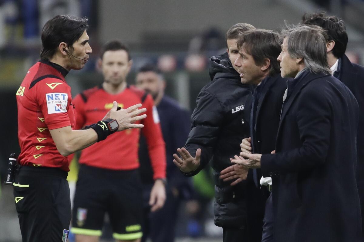 Inter Milan's head coach Antonio Conte, right, argues with referee Gianpaolo Calvarese after one of his players was shown a yellow card during an Italian Cup soccer match between Inter Milan and Napoli at the San Siro stadium, in Milan, Italy, Wednesday, Feb. 12, 2020. (AP Photo/Luca Bruno)